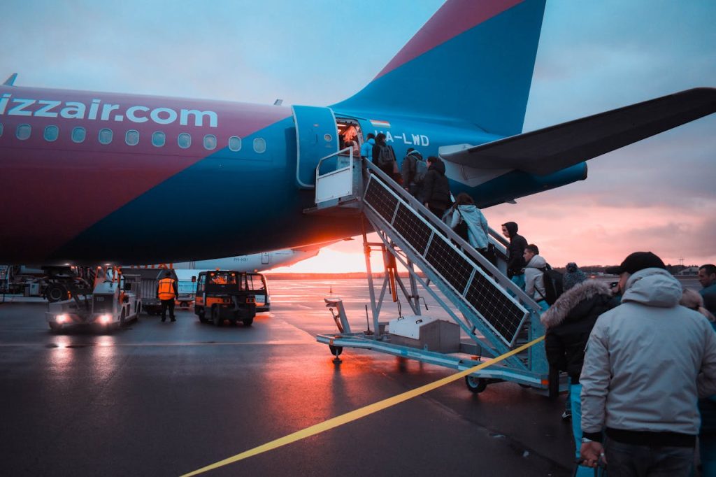 Passengers boarding an airplane at sunset with a vivid sky in the background, capturing a travel moment.